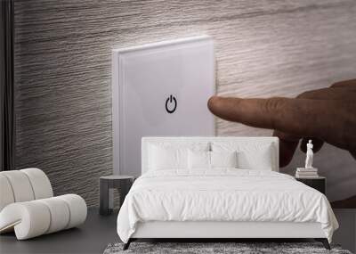 close-up finger turns on the light on the touch switch. A white modern light switch on a white wall. modern design. Wall mural