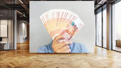 Close-up men's hands hold a wad of Russian money five thousand bills. million rubles in hand Wall mural