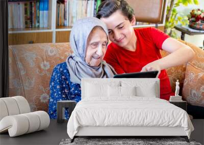 Happy arabic muslim grand mother and her son sitting together on Wall mural