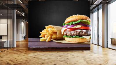 Craft beef burger and french fries on wooden table isolated on black background. Wall mural