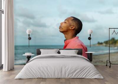 Casual man with black skin breathing fresh air on the beach Wall mural