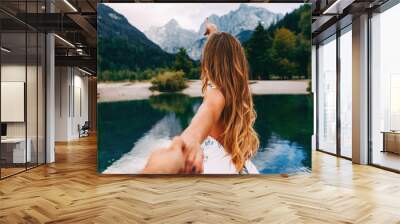 Attractive young woman holding hand of her friend and walking next to the lake Wall mural