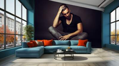 Handsome man posing in studio on dark background Wall mural