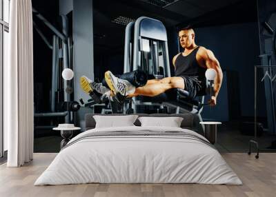 Strong young man doing legs exercise in the gym Wall mural