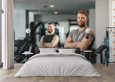 Two Handsome young man posing in a gym and looking at the camera with smile Wall mural