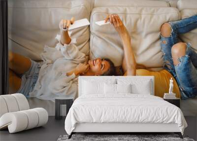 Two young happy woman doing selfie on the sofa Wall mural