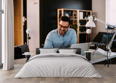 Young business man working at home with laptop and papers on desk Wall mural