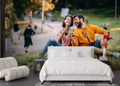 Young happy couple enjoying a park with beer in hand during the summer Wall mural