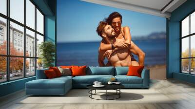 Young happy couple in a embrace on the beach Wall mural