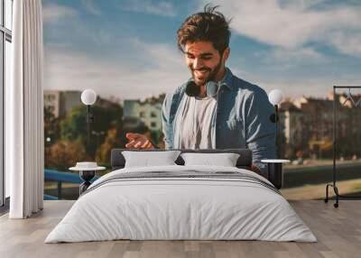 Young happy man using a smartphone  in the city Wall mural