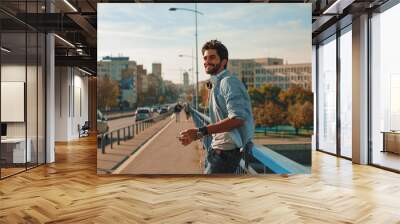 Young happy man using a smartphone  in the city Wall mural