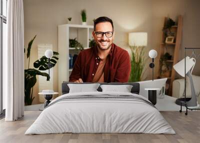 Young man works from home at a desk with a tablet and a laptop Wall mural