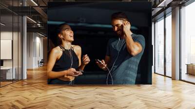 Young sports couple listening to music and laughing Wall mural