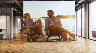 Young woman and man using smartphone by the river Wall mural