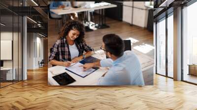 Young woman signing contract with manager Wall mural