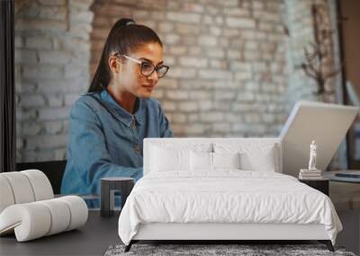 Young woman working on laptop in the office Wall mural