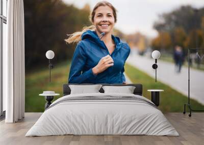 Beautiful adult woman is jogging outdoor on cloudy day in autumn. Wall mural