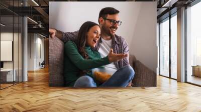 Couple is relaxing at home. They are watching tv. Wall mural