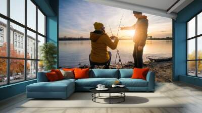 Father and son are fishing on winter day. River fishing. Teenage boy is learning to fish. Wall mural