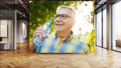 Happy senior man is drinking water in park. Wall mural