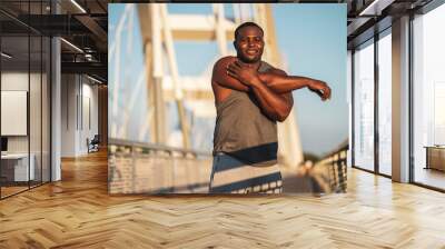 Portrait of young african-american man in sports clothing who is exercising to reduce his body weight. 
 Wall mural