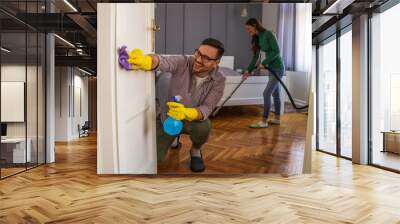 Young happy couple is cleaning their apartment. Wall mural