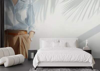 A woman wearing a blue shirt and brown skirt stands in a white room, holding her arm on her hip, captured in a minimalistic interior design concept with professional color grading. Wall mural