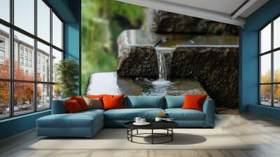 Beautiful three-tiered stone waterfall. Water flowing over rocks. Zen style garden fountain image.  Focused on foreground. Wall mural