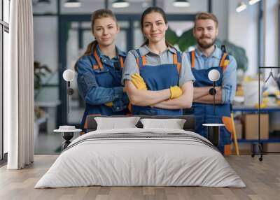 A professional cleaning service team in uniform equipped with cleaning supplies and tools standing in a tidy office space Wall mural