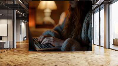 A young woman hands on a laptop keyboard with her face lit by the screen glow in a relaxed home setting Wall mural