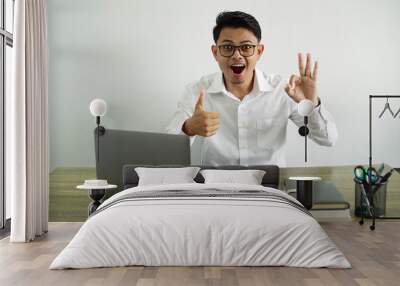 young asian businessman in a workplace showing ok sign and thumb up gesture, wear white shirt with glasses isolated Wall mural