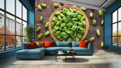 pistachios nuts peeled green in wooden bowl, top view. Wall mural