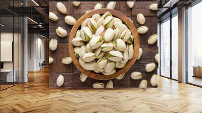 shelled pistachio nuts in wooden bowl, top view. Wall mural