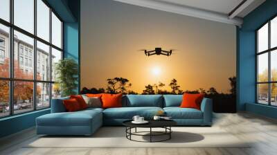 Silhouette of a drone Quadcopter against the backdrop of sunrise in nature in summer. Wall mural