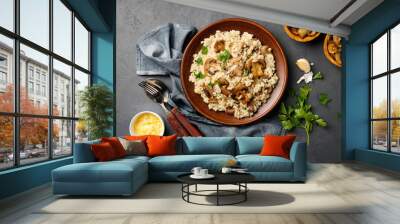 A dish of Italian cuisine - risotto from rice and mushrooms in a brown plate on a black slate background. Top view. Flat lay. Wall mural