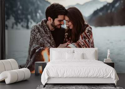 Couple enjoying a cozy moment by a campfire in the snowy mountains during sunset Wall mural