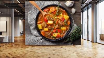 Goulash, beef stew or bogrash soup with meat, vegetables and spices in cast iron pan on wooden table. Hungarian cuisine. Rustic style. Top view. Wall mural