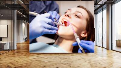 Male dentist treating teeth to young woman patient in clinic. Wall mural