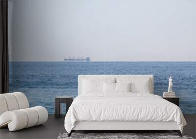 Calm blue sea with the silhouette of a large ship on the horizon Wall mural