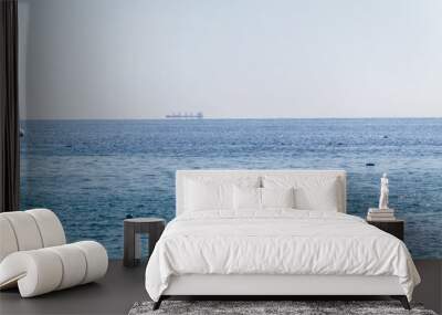 Calm blue sea with the silhouette of a large ship on the horizon Wall mural