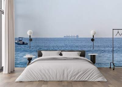 Calm blue sea with the silhouette of a large ship on the horizon Wall mural