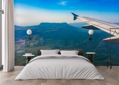 View of airplane wing, blue skies and green land during landing. Airplane window view. Wall mural