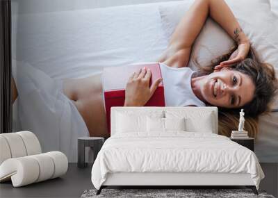 a woman in bed reading a book in the bedroom in the morning Wall mural