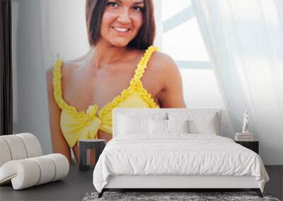 Beautiful tanned woman in yellow swimsuit sunbathes on the beach by the sea Wall mural