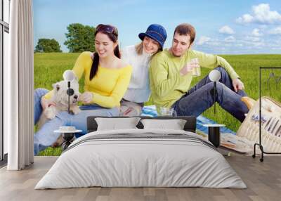 three friends with little white dog at picnic Wall mural