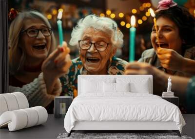 A group of women are celebrating a birthday with a cake and candles Wall mural