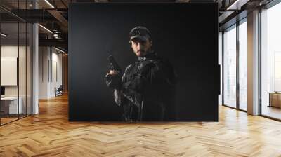 A man with the airsoft rifle in the smoke on the dark background. Special agent concept. Action movie film concept. Wall mural