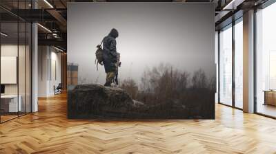 A post apocalypse soldier is walking on a abandoned area with a rifle and backpack. Wall mural