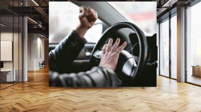 Angry driver is honking and is yelling by sitting of a steering wheel. Road aggression concept. Traffic jam. Wall mural