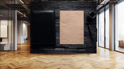 Brown blank paper page with a copy space, leather black book, quill pen and a inkwell on a black wooden table flat lay background. Wall mural